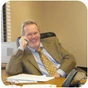 Roger A. Sutherland, seated at his desk with a telephone.